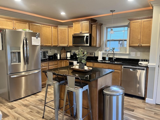 kitchen with decorative light fixtures, stainless steel appliances, dark stone counters, sink, and ornamental molding