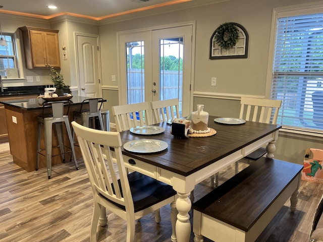 dining space featuring french doors, ornamental molding, and light hardwood / wood-style flooring