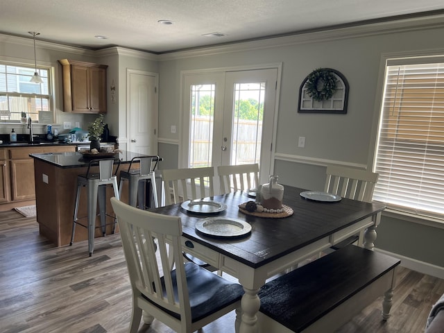 dining space with a textured ceiling, french doors, sink, ornamental molding, and hardwood / wood-style flooring