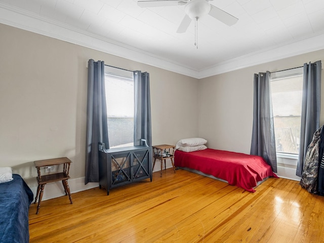 bedroom with ceiling fan, crown molding, and wood-type flooring