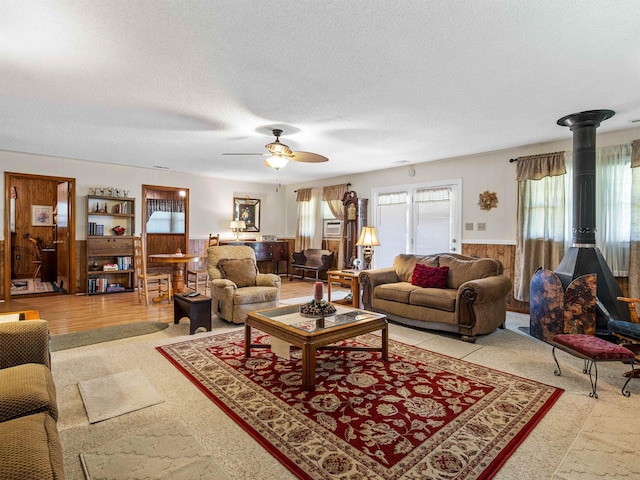 living room with a textured ceiling, ceiling fan, and wooden walls