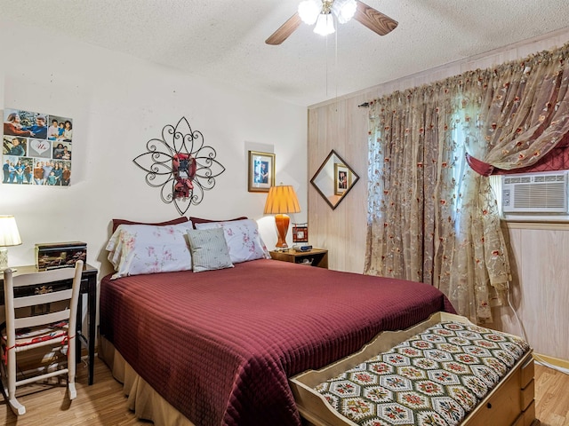 bedroom with wood-type flooring, a textured ceiling, ceiling fan, and cooling unit