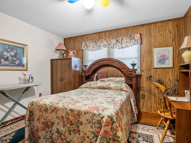 bedroom with wood walls, ceiling fan, and a textured ceiling