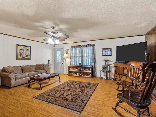 living room with a textured ceiling, ceiling fan, ornamental molding, and wood-type flooring