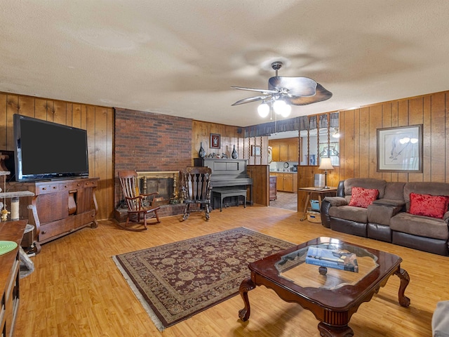 living room featuring a textured ceiling, wood walls, ceiling fan, and light hardwood / wood-style floors