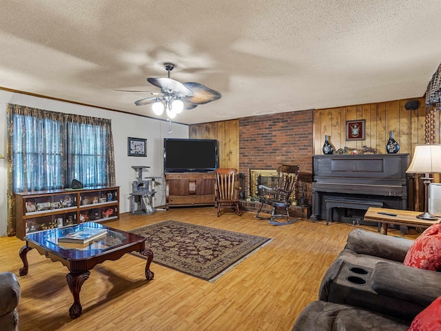 living room with a textured ceiling, ceiling fan, wood-type flooring, wood walls, and crown molding