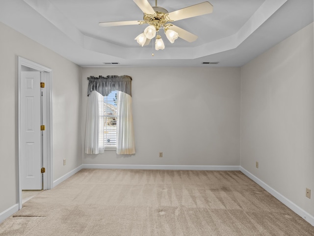 unfurnished room with ceiling fan, light carpet, and a raised ceiling