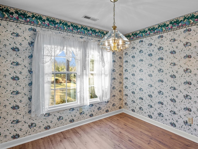 unfurnished dining area featuring an inviting chandelier and wood-type flooring