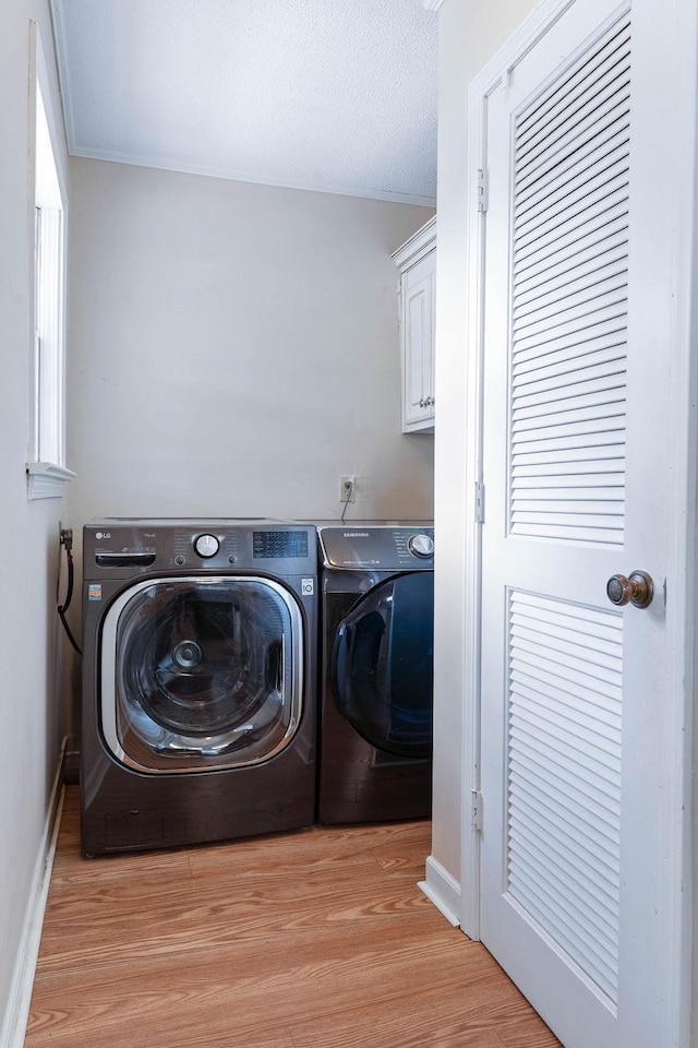 washroom featuring cabinets, light wood-type flooring, and independent washer and dryer