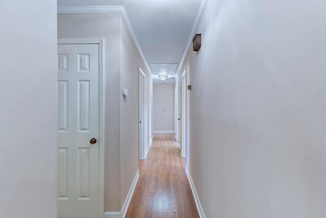 hallway featuring a textured ceiling, ornamental molding, and hardwood / wood-style flooring