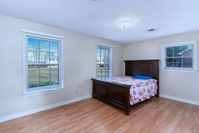 bedroom with a textured ceiling and light wood-type flooring