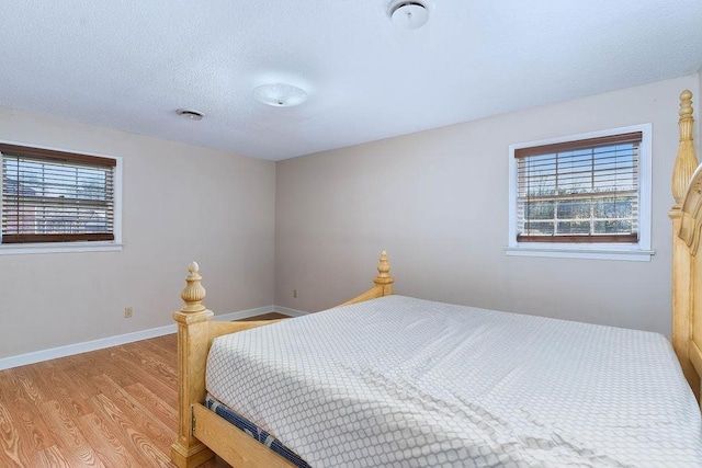 bedroom featuring light wood-type flooring, a textured ceiling, and multiple windows