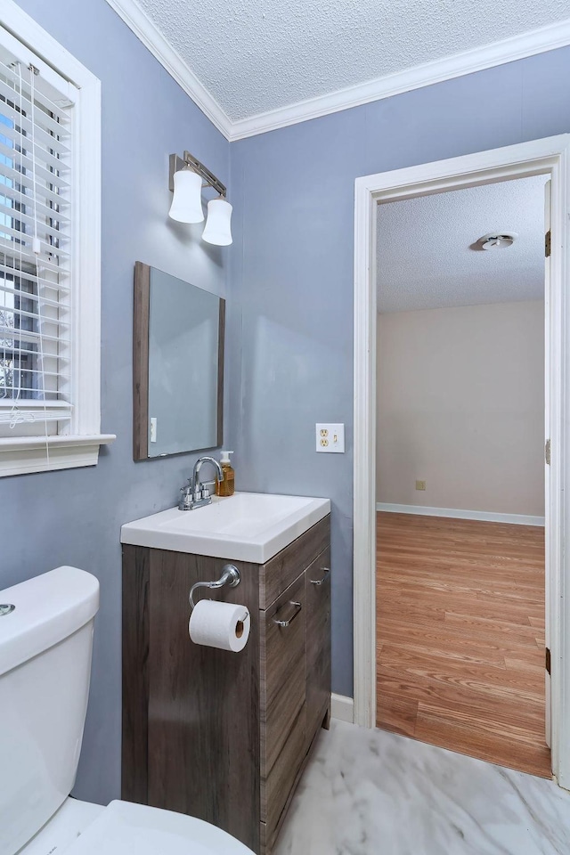 bathroom featuring hardwood / wood-style floors, toilet, crown molding, vanity, and a textured ceiling