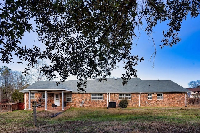 back of property featuring central air condition unit and a lawn