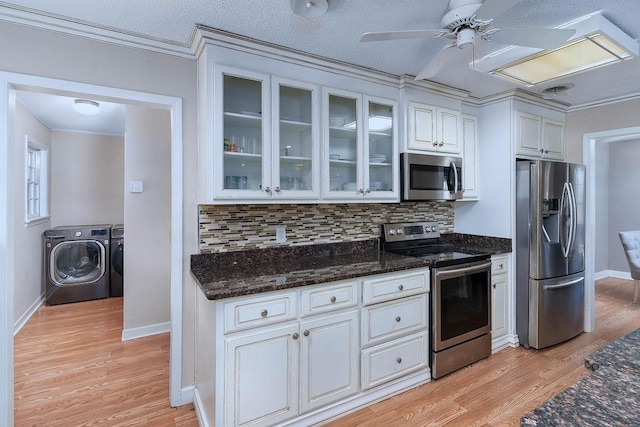 kitchen featuring stainless steel appliances, washing machine and dryer, light wood-type flooring, backsplash, and ceiling fan