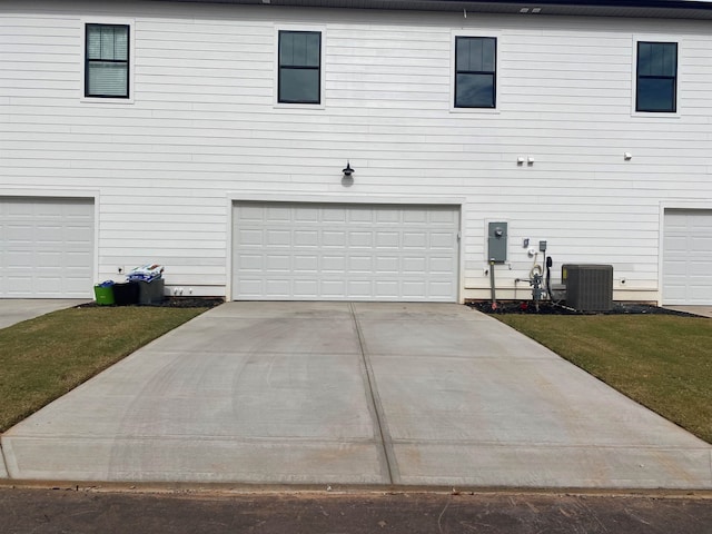 view of side of property with central air condition unit, a yard, and a garage