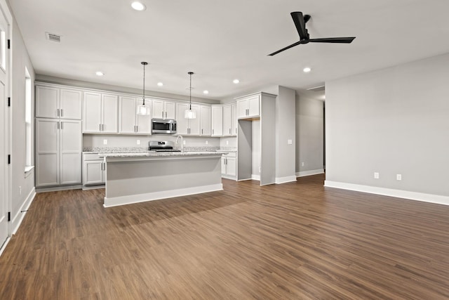 kitchen featuring decorative light fixtures, stainless steel appliances, dark wood-type flooring, and a kitchen island with sink