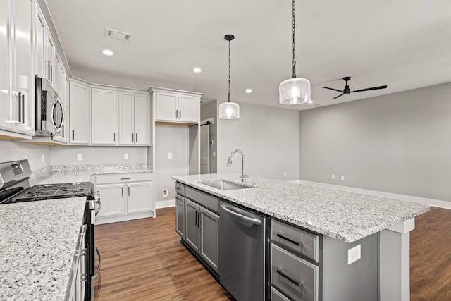 kitchen featuring stainless steel appliances, sink, white cabinets, ceiling fan, and an island with sink