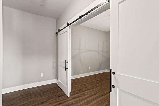 spare room with a barn door and dark wood-type flooring