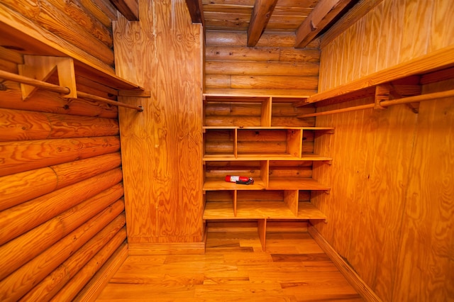 walk in closet with light hardwood / wood-style flooring and beam ceiling