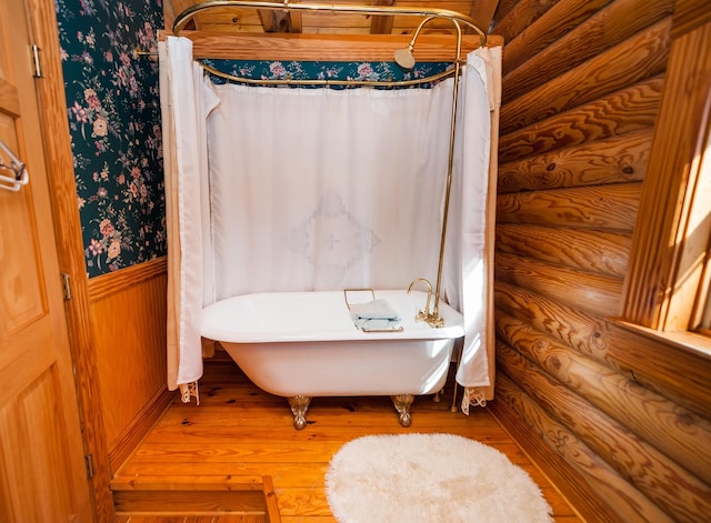 bathroom featuring log walls, a bath, and hardwood / wood-style floors