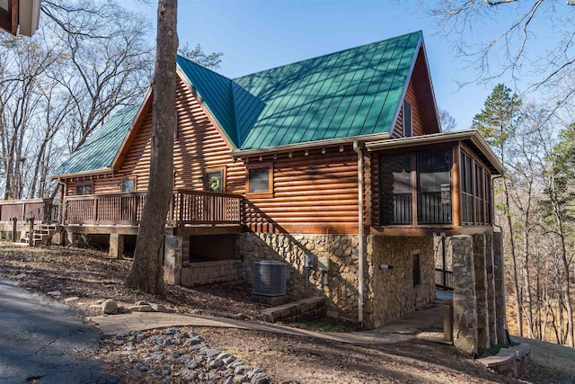 view of side of property featuring central AC, a sunroom, and a wooden deck