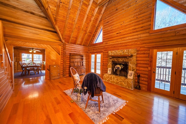 unfurnished dining area with rustic walls, hardwood / wood-style floors, high vaulted ceiling, a fireplace, and wooden ceiling