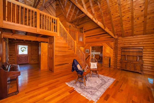 sitting room with beam ceiling, wood ceiling, log walls, and high vaulted ceiling