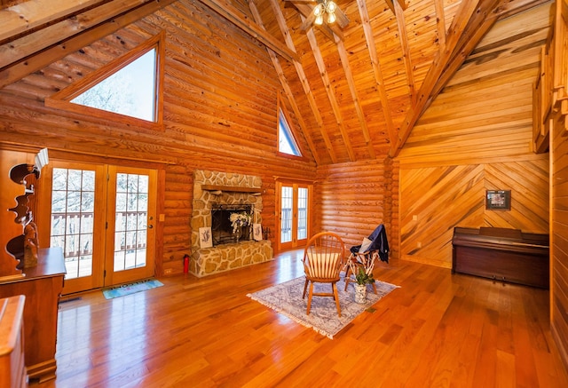 unfurnished living room featuring a fireplace, high vaulted ceiling, hardwood / wood-style flooring, and rustic walls