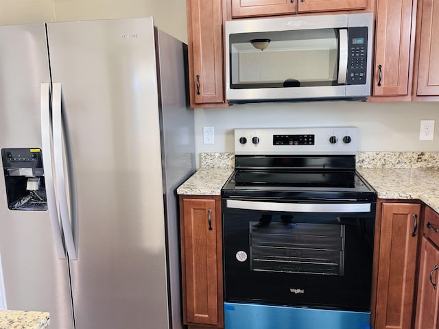 kitchen with light stone counters and appliances with stainless steel finishes