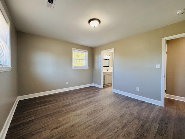 unfurnished bedroom featuring ensuite bath and dark hardwood / wood-style floors