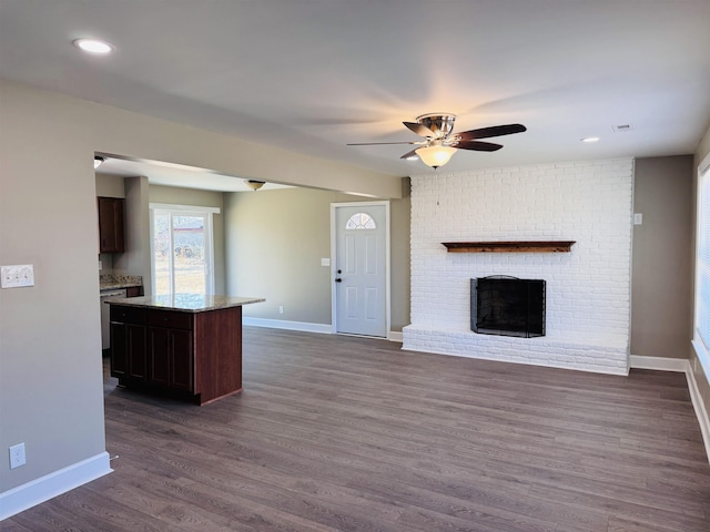 unfurnished living room with ceiling fan, a brick fireplace, and dark hardwood / wood-style floors