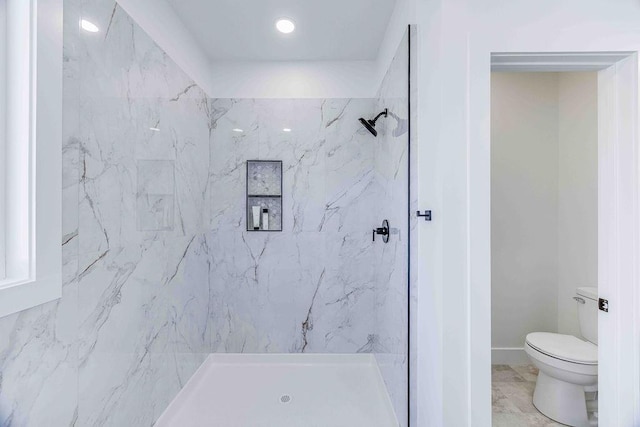 bathroom with a tile shower and toilet