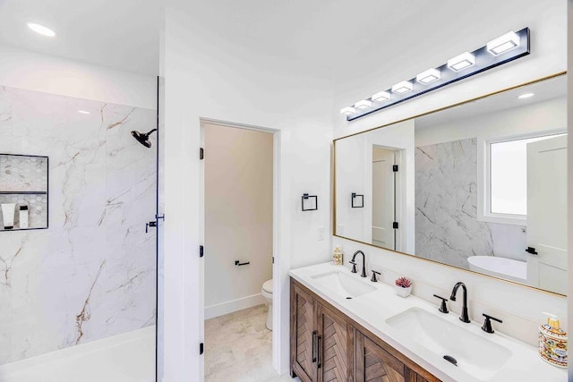 bathroom with toilet, tiled shower, and vanity