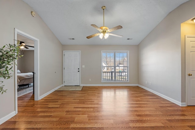 foyer entrance with light wood-type flooring, vaulted ceiling, and a textured ceiling