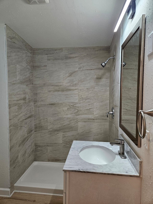 bathroom with vanity and tiled shower