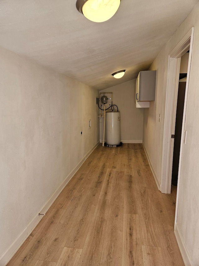 basement featuring water heater and light hardwood / wood-style flooring