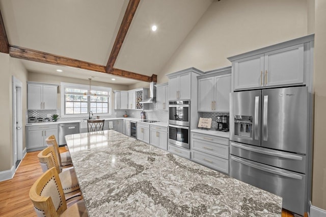 kitchen with light stone countertops, appliances with stainless steel finishes, gray cabinets, and beamed ceiling