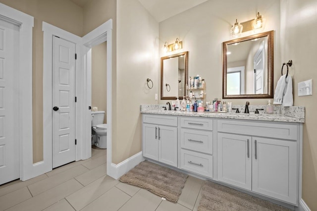 bathroom with toilet, vanity, and tile patterned flooring