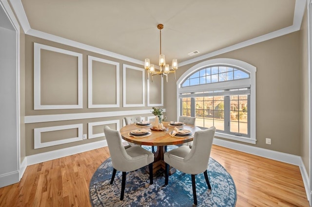 dining space featuring light hardwood / wood-style flooring, ornamental molding, and an inviting chandelier