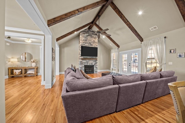 living room with ceiling fan, light hardwood / wood-style flooring, french doors, and a stone fireplace