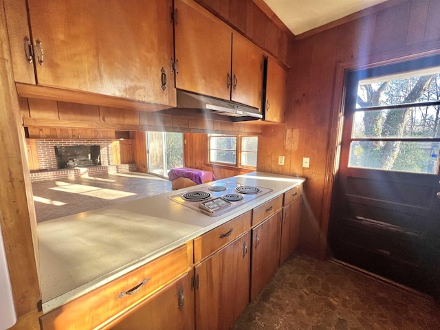 kitchen featuring a brick fireplace, wood walls, and stovetop