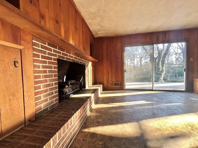 unfurnished living room featuring a brick fireplace and wooden walls