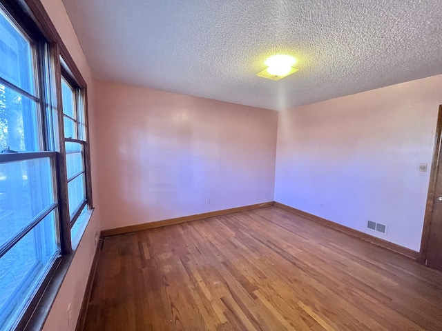 empty room featuring a textured ceiling and hardwood / wood-style flooring