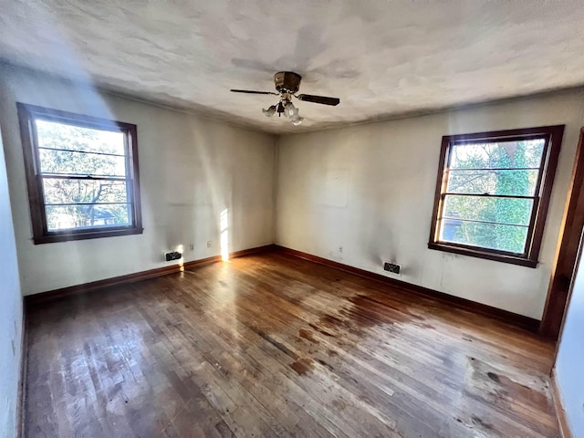 spare room featuring ceiling fan, dark hardwood / wood-style flooring, and plenty of natural light