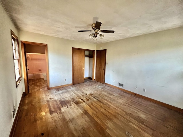 unfurnished bedroom with ceiling fan, connected bathroom, hardwood / wood-style flooring, and a textured ceiling