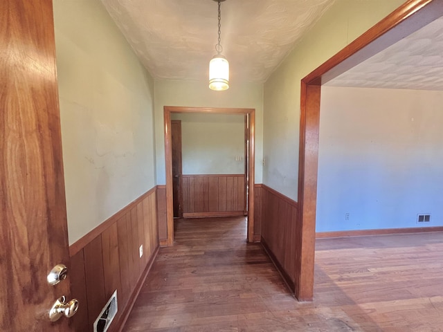 corridor with a textured ceiling and wood-type flooring