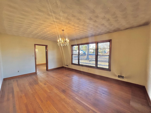 empty room with hardwood / wood-style floors and a notable chandelier