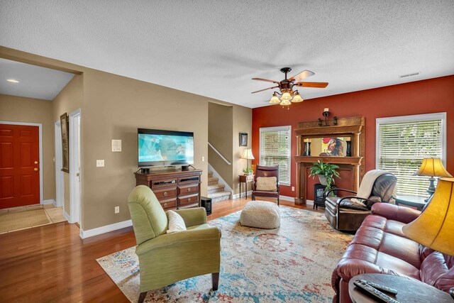 living room with ceiling fan, a textured ceiling, and hardwood / wood-style flooring