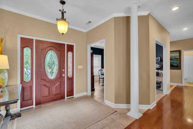 foyer featuring light tile patterned floors, ornamental molding, and ornate columns